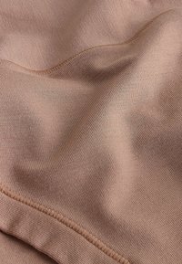 Svetlo hnedá tkanina s hladkou, mierne lesklou textúrou, s jemným šitím pozdĺž okrajov a jemnými záhybmi.