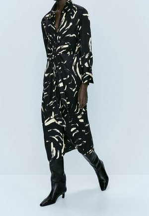 Black dress with cream abstract patterns, long sleeves, and a button front, paired with knee-high black pointed boots.