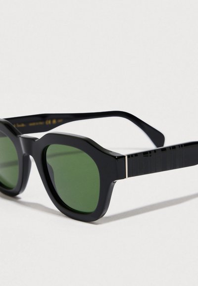 Mustad päikeseprillid roheliste läätsedega, kandiliste raamidega ja tekstuurse aktsendiga prillikäppadel, valmistatud kergest plastikust.