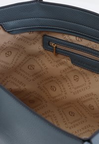 Interior de un bolso de cuero gris oscuro con un forro de tela beige que presenta el logo repetido "CAFE NOIR", incluyendo un bolsillo con cremallera a un lado.