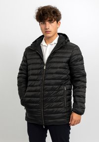 Giacca a vento nera con cuciture orizzontali, chiusura frontale con cerniera e cappuccio. Dotata di tasche laterali e texture liscia e lucida.