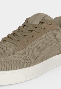 Baskets en tricot taupe avec accents en daim, lacets ton sur ton et semelle en caoutchouc blanc texturé, marquées "Marc O'Polo" sur le côté.