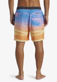 Shorts de bain avec un dégradé allant du bleu à l'orange, dotés d'une taille élastique et d'une poche arrière avec un rabat bleu clair.