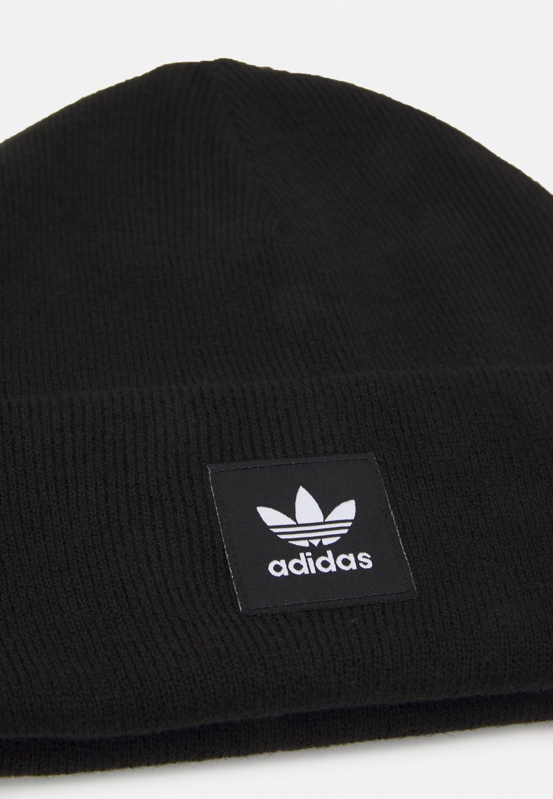 Czarna dziana beanie o teksturowanym prążkowanym wzorze oraz kwadratowej czarnej łatce z białym logiem Adidasa. Prosty i funkcjonalny design.