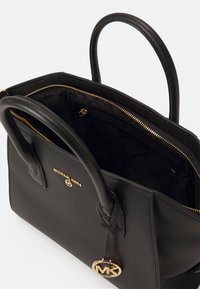 Černá kožená kabelka s pevnou strukturou, horními držadly, zlatými kovovými doplňky, kapsou na zip a logem na vnější straně.