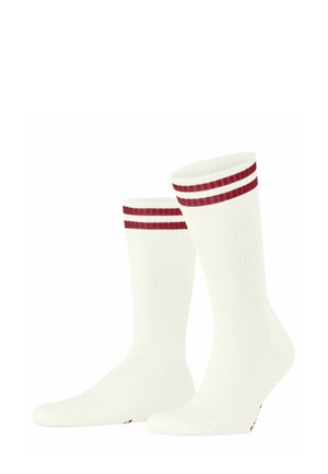 Chaussettes blanches avec une texture côtelée, présentant deux rayures rouges horizontales en haut. Forme de tube standard avec un orteil renforcé.
