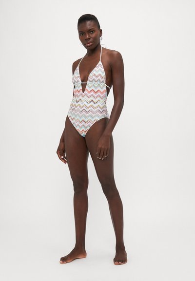 Costume da bagno multicolore con motivo zigzag in bianco, caratterizzato da un profondo scollo a V, spalline a halter e lati aperti con cosce alte.