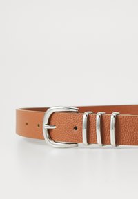 Tan leather belt with a textured finish, featuring a silver metal buckle and three polished metal keepers for secure adjustment.