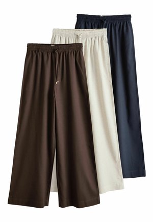 Tre par vidde bukser med elastiske taljebånd og bindebånd, i brun, beige og mørkeblå, lagdelt fra venstre mod højre.