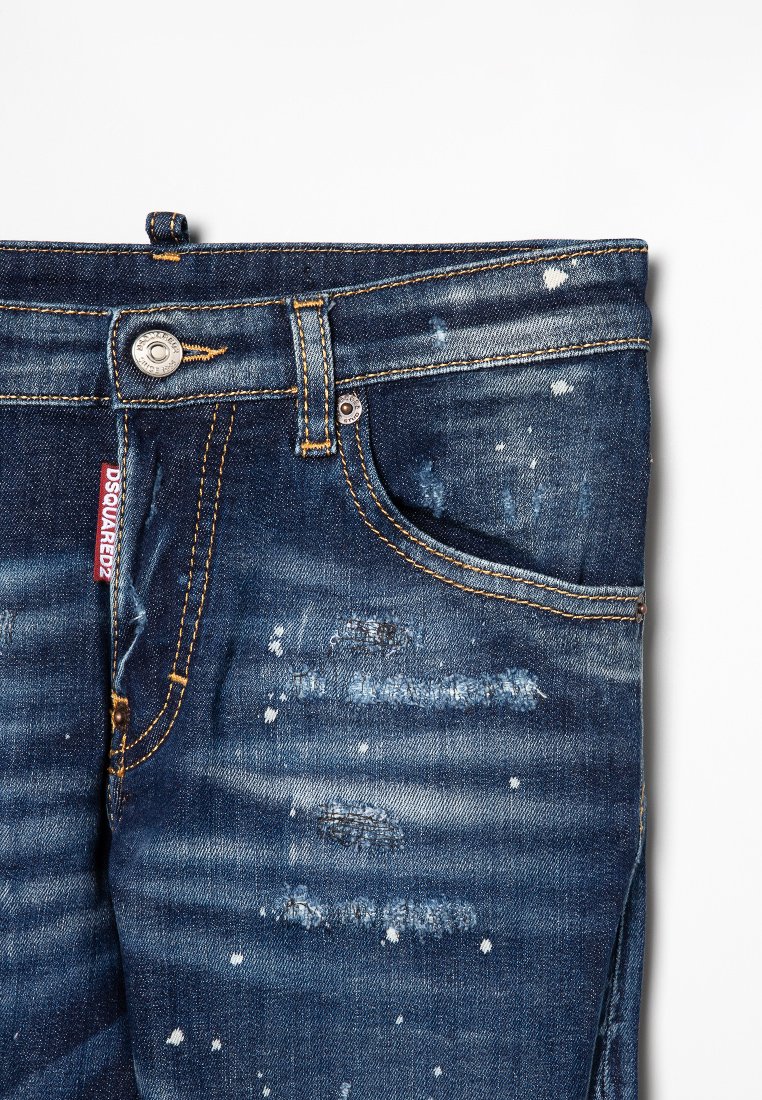 Jeans in denim blu scuro con aree strappate, leggere macchie bianche e cuciture arancioni. Includono una tasca frontale e chiusura con bottone in metallo.