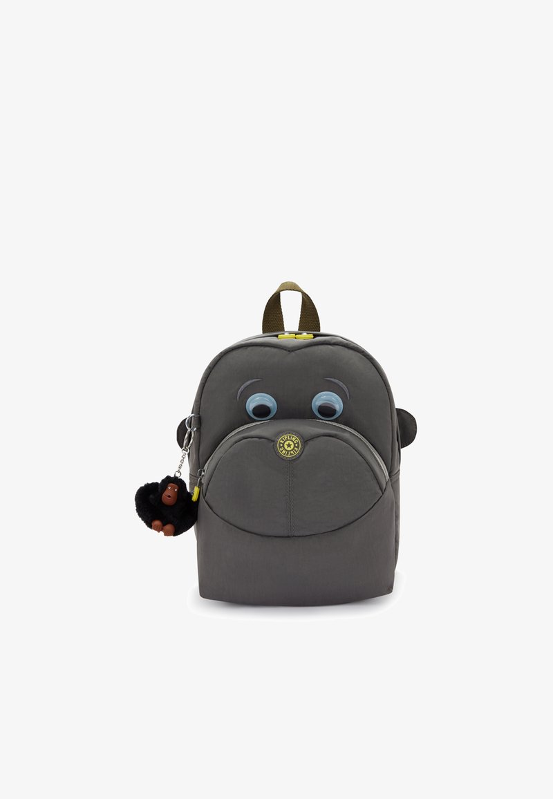 Sac à dos en tissu gris avec de grands yeux de dessin animé, une poche ronde zippée et un porte-clés en forme de singe attaché. Il présente une poignée verte et des accents de logo.