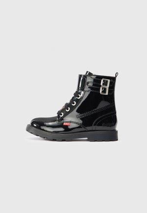 Botas de tornozelo em patente preto com atacadores à frente, fivelas laterais, sola de borracha e logótipo vermelho contrastante ao lado. Textura suave e brilhante.