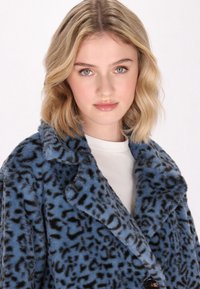 Abrigo de piel sintética azul con estampado de leopardo negro, con cuello de muesca y cierre frontal con botones. Textura suave y corte relajado.