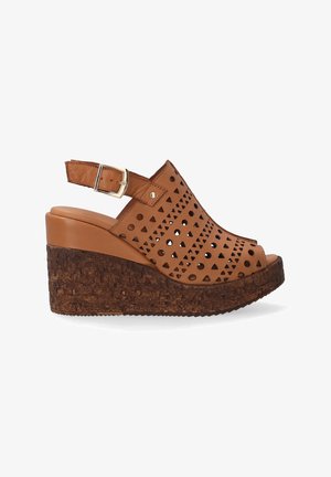 Brown wedge sandals made of leather with perforated geometric patterns. Cork-like heel, adjustable buckle strap, open-toe design.