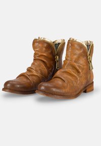 Braune Leder-Stiefeletten mit durchbrochener Struktur, goldenen Reißverschlüssen und gefaltetem Oberteil. Flacher Holzabsatz mit einem bedruckten Stofffutter.