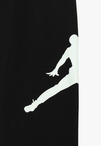 Tejido negro con una silueta blanca brillante de una persona saltando, mostrando un movimiento atlético. Diseño minimalista, textura suave.