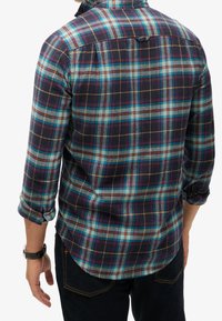 Miesten flanellipaita laivastonsinisessä, turkoosissa ja punaisessa ruutukuviossa, jossa on napillinen kaulus, pitkät hihat ja kaartuva helma.