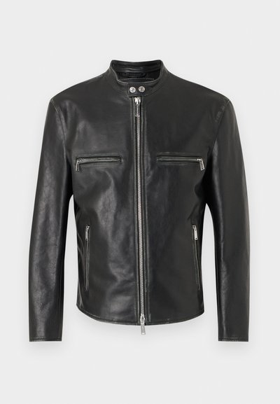 Μαύρο δερμάτινο μπουφάν με όρθιο γιακά, κεντρικό ασημένιο φερμουάρ, δύο οριζόντια φερμουάρ στο στήθος και δύο κάθετες πλαϊνές τσέπες με φερμουάρ.