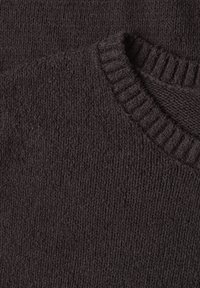 Close-up of dark brown knitted fabric showing ribbed collar and textured stitch pattern on soft sweater material.