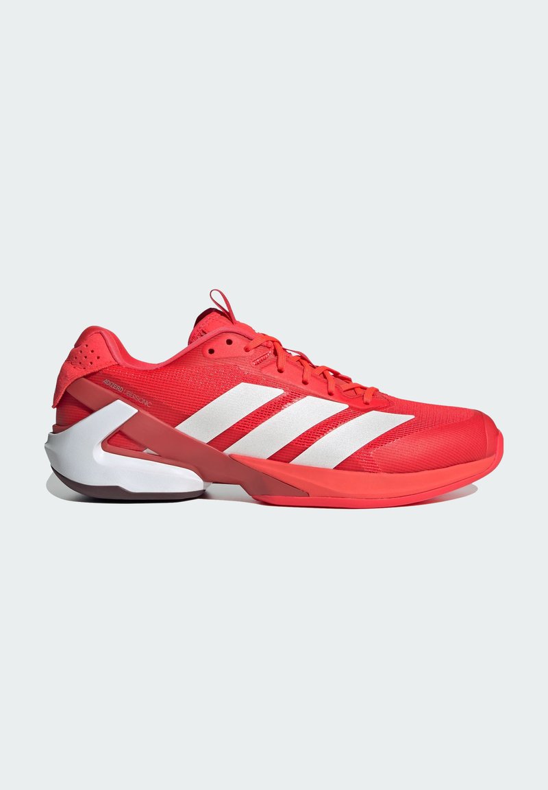 Chaussure de sport rouge avec tige en mesh, trois rayures blanches, contre-collier renforcé et design de semelle intermédiaire incurvée blanche.