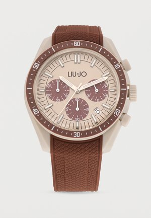 Round beige and brown chronograph wristwatch with textured brown strap, three subdials, date window, and silver hour markers and hands.