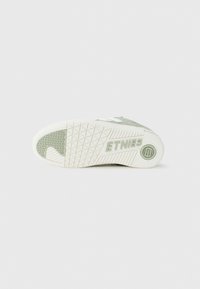 Baskets en daim vert avec semelle en caoutchouc blanc. Présente une texture antidérapante et un motif de semelle. Logo "ETNIES" embossé sur le côté.