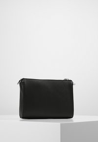 Svart kosmetikväska med dragkedja som har en slät konstlädertextur, rektangulär form och silverfärgade detaljer.