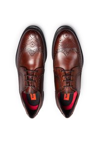 Scarpe eleganti in pelle marrone scuro con design a punta d'ala, fori punzonati e fodera rossa a contrasto. Presentano lacci rotondi e una punta leggermente affilata.