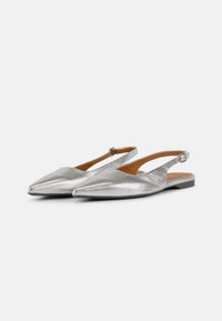Zapatos slingback plateados con puntera afilada, suela plana y un diseño recortado. Cuentan con una delgada correa en el tobillo y una textura metálica lisa.