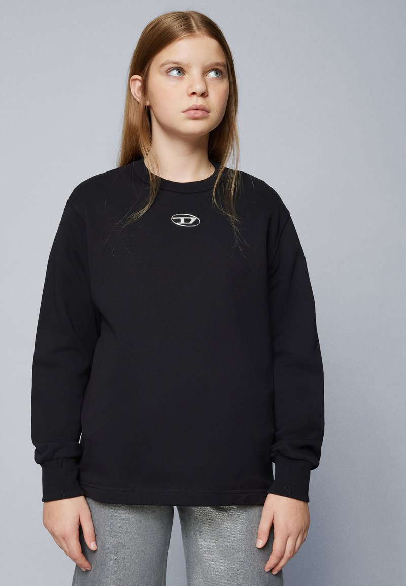 Sudadera negra de manga larga con puños acanalados y un escote redondo, que presenta un pequeño logo plateado en el pecho. Tejido suave de algodón.