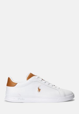 Vita syntetiska sneakers med en konjaksbrun läderdetalj vid hälen, snörning framtill och broderad logotyp på sidan. Rund tå och texturerad yttersula.