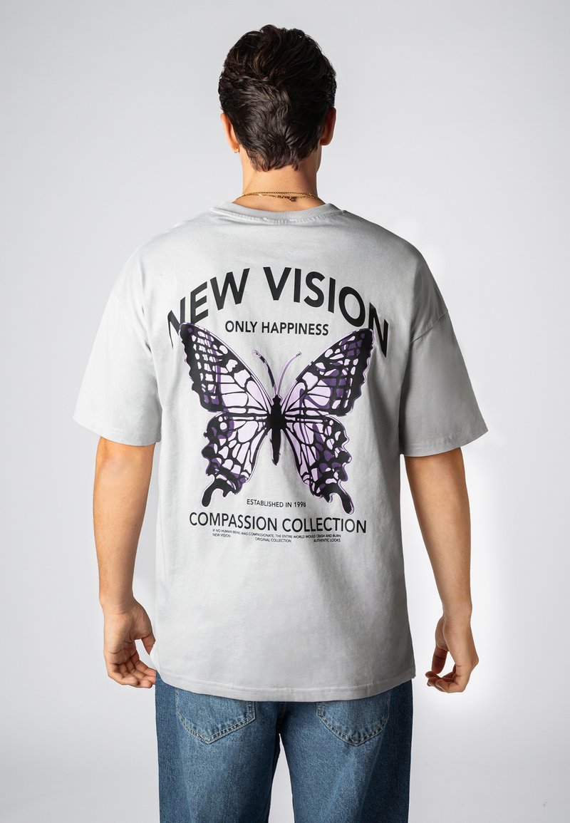 Gray t-shirt featuring a large purple butterfly graphic on the back, with "NEW VISION ONLY HAPPINESS" and "COMPASSION COLLECTION" text.