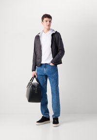 Jachetă ușoară neagră cu glugă, tricou polo alb, blugi denimul albastru, geantă de piele neagră și adidași negri cu talpă groasă.
