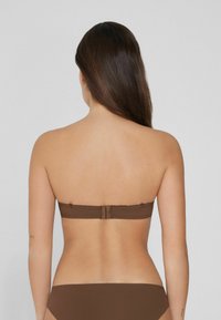 Bordowy bikini w formie bandeau z zapięciem na plecach. Gładki materiał z minimalną ilością szwów i dopasowane majtki bikini.