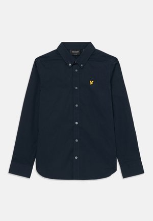 Chemise à manches longues bleu marine avec un col boutonné, en coton. Présente un petit logo doré en forme d'aigle sur la poitrine et une fermeture à boutons.