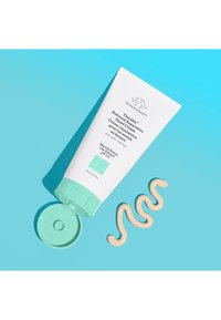 White tube with a mint-green cap, labeled "Therabalm Hand Cream." Creamy product swirled beside the tube on a light blue background.