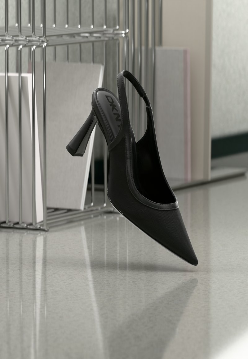 Μαύρο γόβα με μυτερή μύτη και λουράκι στο πίσω μέρος, με το λογότυπο DKNY στο εσωτερικό, τοποθετημένο σε έναν ανακλαστικό δάπεδο κοντά σε μεταλλική βάση που κρατά καμβάδες.