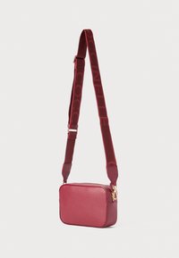 Borsa a tracolla rossa in pelle con forma rettangolare. Presenta una tracolla a fantasia color bordeaux e dettagli in oro. Texture liscia.