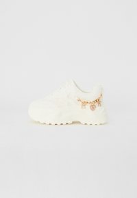 Baskets blanches avec revêtement texturé, semelle épaisse et chaîne latérale avec des détails en cœur et en charme. Comprend des lacets et un col rembourré.