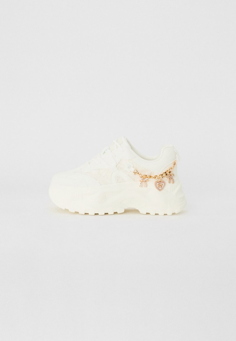 Baskets blanches avec revêtement texturé, semelle épaisse et chaîne latérale avec des détails en cœur et en charme. Comprend des lacets et un col rembourré.