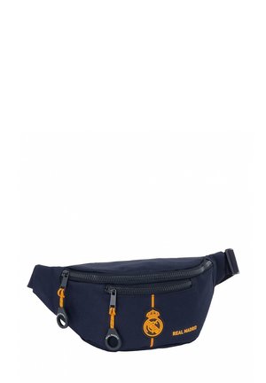 Marsupio navy realizzato in tessuto resistente, con una tasca anteriore con cerniera, accenti arancioni e il logo del Real Madrid. Include una cintura regolabile.