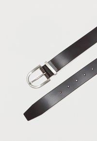 Μαύρη δερμάτινη ζώνη με ασημένια ορθογώνια αγκράφα. Ο ιμάντας διαθέτει ομοιόμορφα κατανεμημένες τρύπες για ρύθμιση και μια απαλή επιφάνεια.