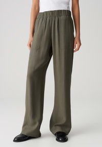 Pantalons larges, verts olive avec une taille élastique et deux poches avant ; texture lisse et tissu léger.