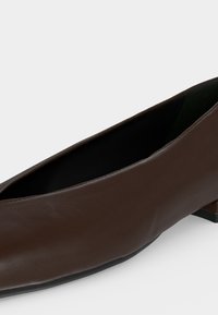 Chaussure femme en cuir marron à talon bas, bout carré et texture lisse sur fond blanc.