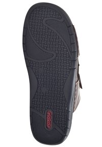 Zwarte rubberen schoenzool met gestructureerde grippatronen, voorzien van een logo. Het ontwerp omvat gebogen lijnen en een verhoogde, gevoerde rand.