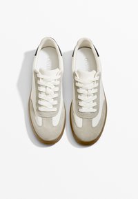 Hellebeige Sneaker aus Wildleder und Mesh-Materialien mit weißen Akzenten, runden Schnürsenkeln und einer braunen Gummisohle. Draufansicht.