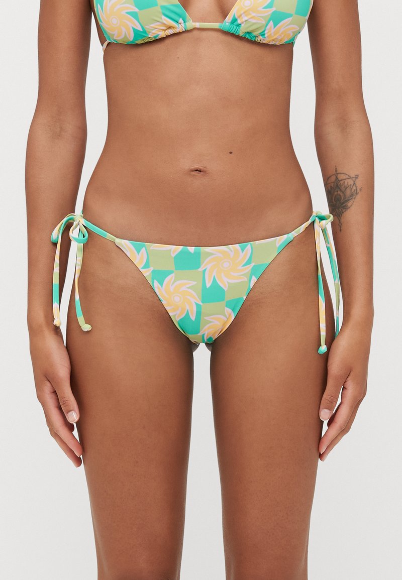 Bikini-Höschen mit Blumenmuster und Bindebändern an den Seiten, in sanften Farben von Grün, Gelb und Pfirsich auf einem Schachbrett-Hintergrund.