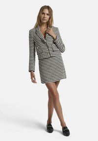 Zwart-wit houndstooth blazer met bijpassende rok, voorzien van gouden knopen en een getailleerde pasvorm. Gladde stof met een gestructureerd ontwerp.