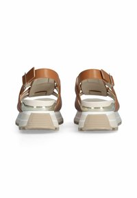 Brown adjustable sandals with a wide strap, open-back design, and a cushioned beige sole featuring textured accents and metallic detailing.