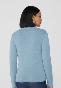Suéter de punto azul claro con un acabado texturizado, con cuello y mangas largas, visto desde la parte de atrás.